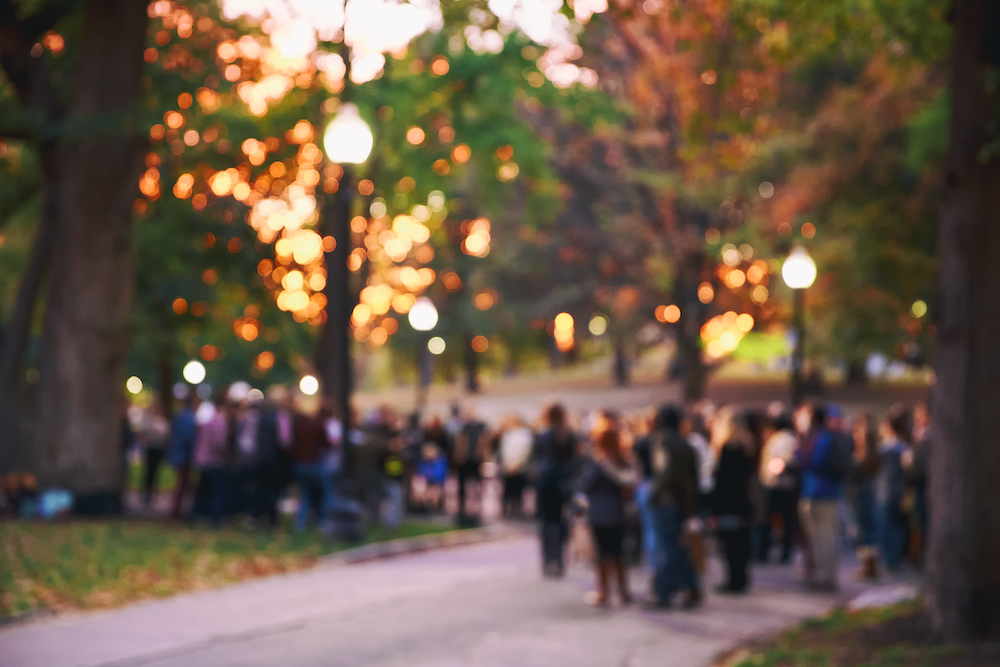 blurry picture of fall colored leaves with people outside for an event