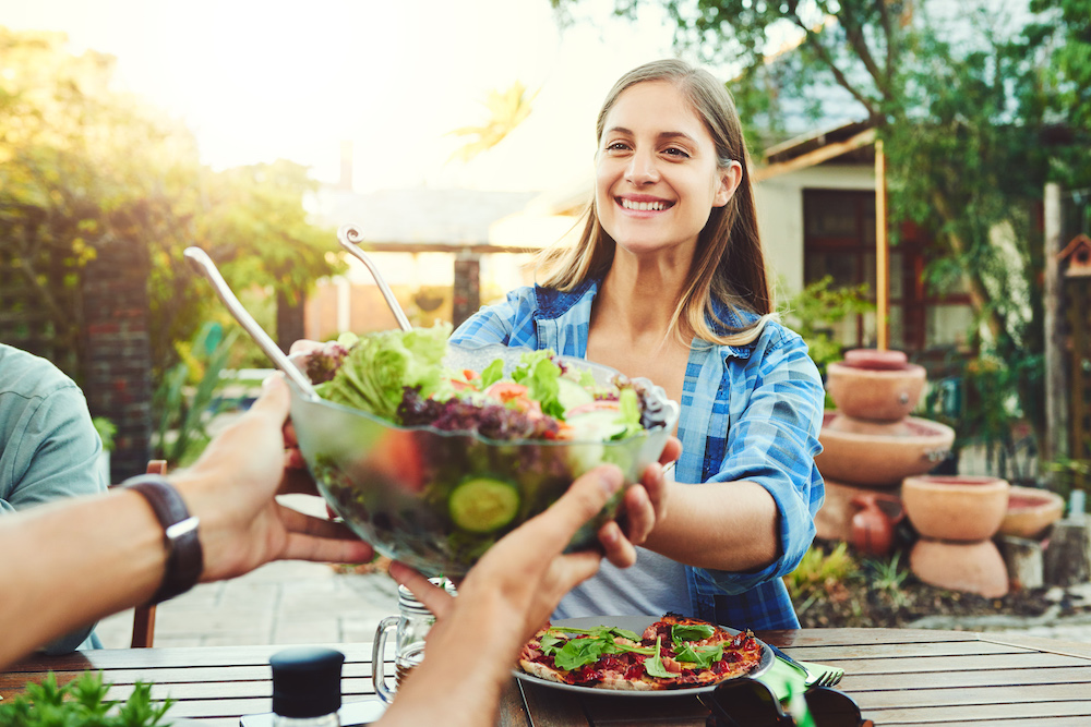 woman taking a bowl of salad from someone